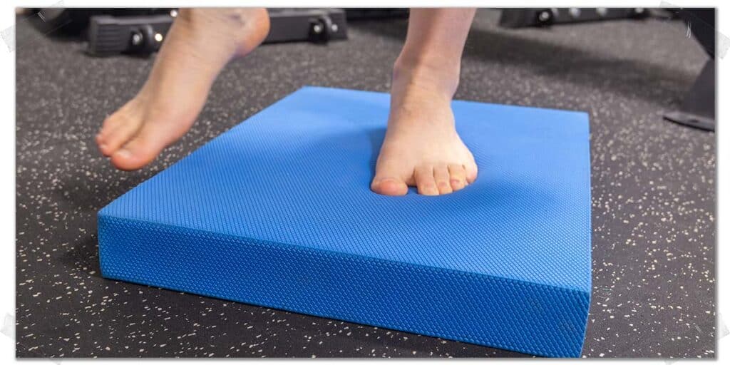 Performing an ankle stability exercise using an Air-X pad to improve ankle strength.
